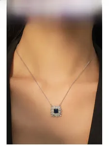 Détail macro du pendentif tournesol avec saphir bleu et diamants sur le cou du modèle