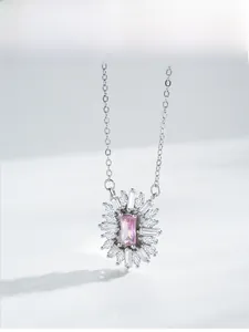 Macro detail of silver sunflower pendant featuring pink rectangular zircon and sparkling pavé