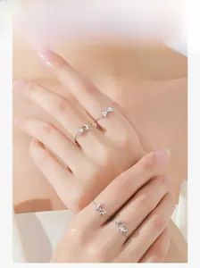 Detail of silver S925 bow, star-moon, and love chain rings worn on a hand