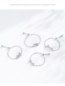 Detail of four S925 sterling silver chain rings featuring butterfly, moon and love charms