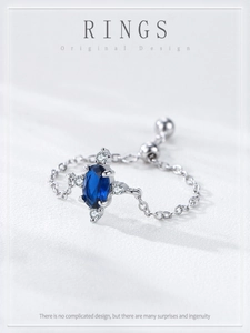 Detail view of adjustable silver chain ring with oval sapphire blue stone and zircons