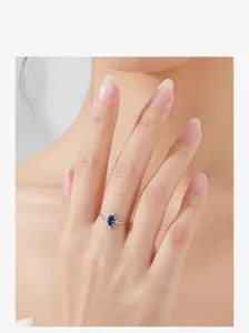Detailed view of an oval blue gemstone ring with silver chain band on a model finger