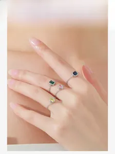 Detail of four-piece gold link chain rings set with emerald, sapphire, pink, and yellow gems