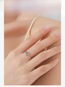 Close-up of a silver chain ring featuring colorful zircon stones on a model's finger