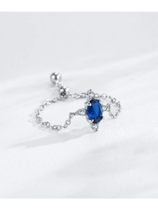 Macro detail of adjustable chain ring with oval blue gemstone and cubic zirconia