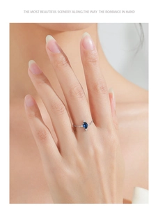 Close-up of a 925 silver chain ring with oval blue gemstone and white zircon accents