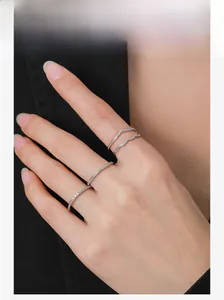Close-up of minimalist S925 silver wave rings set worn on fingers with a dark suit background