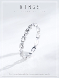 Macro shot of silver chain link ring with sparkling inset diamonds on grey surface