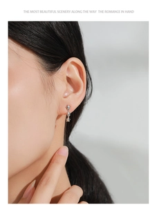 Close-up of minimalist 925 sterling silver triple star drop earrings worn by a model