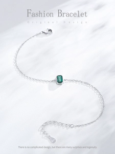 Macro shot of S925 silver bracelet featuring emerald-cut green stone and O-chain detail