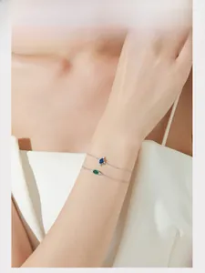 Model wearing vintage S925 silver bracelets with blue and emerald green oval zircons