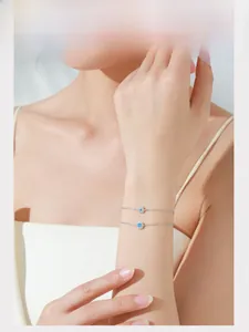 Detail of S925 sterling silver bracelets with blue flower and star charms on model wrist