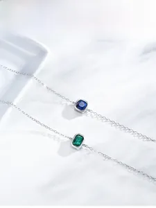 Detailed view of silver bracelets featuring square blue and green gemstone pendants