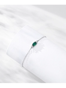 Macro shot of silver bracelet showing emerald green oval zircon stone and fine chain link