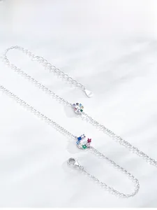 Close-up of S925 silver horseshoe bracelet with colorful zircon stones on white texture