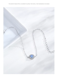 Detailed close-up of a silver bracelet featuring a blue gemstone with rhinestone halo