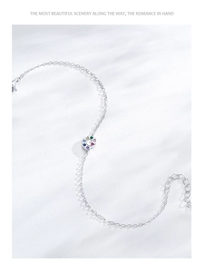 Macro detail of silver U-shaped horseshoe bracelet with colorful zircon stones on white background