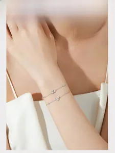 Model wearing a layered S925 silver bracelet set with star, moon, and butterfly charms