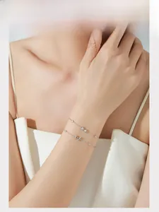 Detail of S925 sterling silver bow bracelets set with cubic zirconia on model's wrist
