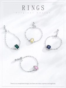 Close-up of four S925 silver chain rings with colorful emerald and oval cut zircons