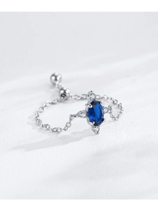 Macro shot of silver chain ring with oval blue zircon and tiny white stones on leather