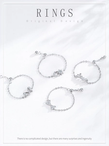 Detalle de cuatro anillos de cadena ajustables en plata S925 con diseños de lazo y amor