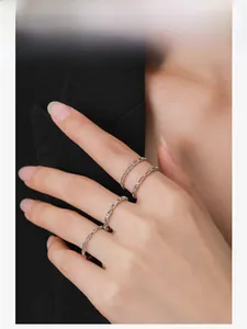 Detailed view of three minimalist S925 silver chain rings worn on a hand over black blazer