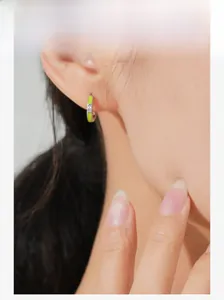 Detail of silver S925 earring with lime green enamel and a tiny diamond on ear lobe