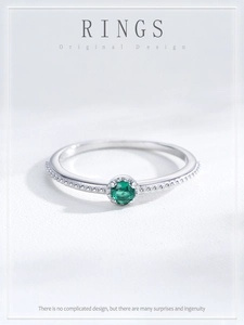 Macro shot of silver ring featuring green emerald-style stone and milgrain band details