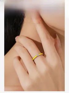 Detail of silver S925 ring with yellow enamel and small center gemstone on finger