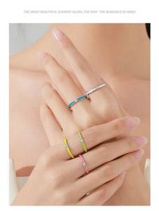 Close-up of five colorful enamel rings with minimalist silver bands and small zircon stones