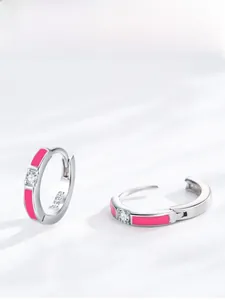 Vista macro di orecchini S925 in argento con smalto rosa e un piccolo diamante