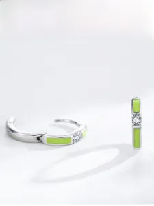 Detailed view of silver hoop earrings featuring green enamel inlay and a small central zircon