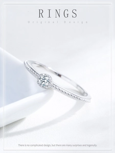 Detailed view of S925 sterling silver ring with milgrain band and zircon on white ceramic