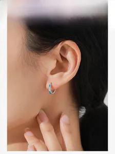 Close-up of S925 sterling silver hoop earring with blue enamel and white zircon on ear