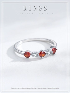 Macro shot of silver ring with three round red rubies and white zirconias in line