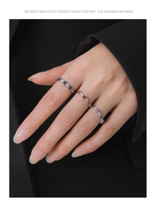 Three minimalist silver rings featuring sapphire blue, ruby red, and purple gemstones on a hand