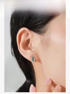 Close-up of model wearing teardrop silver earrings with green stones and zircons
