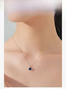 Close-up of S925 sterling silver necklace with a round blue sapphire zircon pendant on model