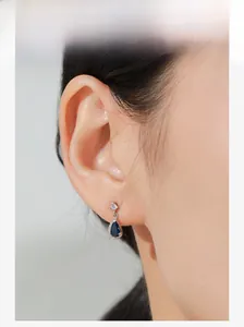 Dettaglio ravvicinato di orecchini a goccia in argento 925 con zircone blu su orecchio