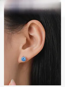 Close-up of minimalist S925 sterling silver stud earring with round blue zircon on model