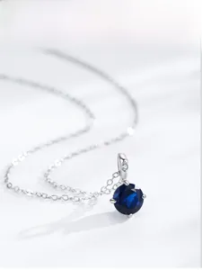Detail of a round blue sapphire zircon pendant on a silver S925 chain necklace