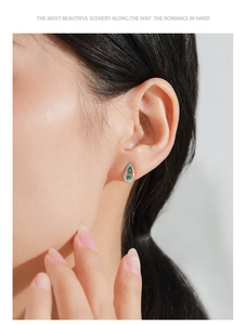 Close-up of model wearing silver teardrop earrings with green zircon and pavé crystals
