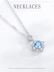 Detailed view of silver flower pendant featuring a deep blue zircon and surrounding crystals