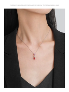 Detail of S925 silver necklace featuring pink and red teardrop gems on a female model