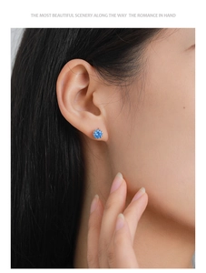 Detailed close-up of a blue zircon stud earring featuring a classic six-prong silver setting