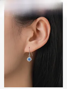 Close-up of S925 sterling silver flower drop earring with sea blue zircon on model