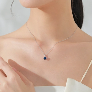 Elegant S925 sterling silver necklace with round blue sapphire pendant worn on a model