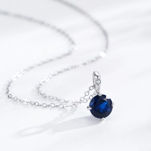 S925 Sterling Silver necklace with a round deep blue sapphire zircon pendant on white surface