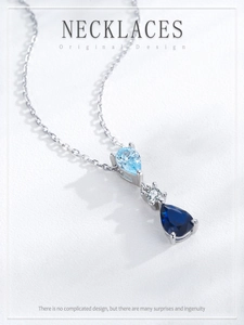 Close-up of S925 silver necklace with gradient blue teardrop zircon stones on white texture